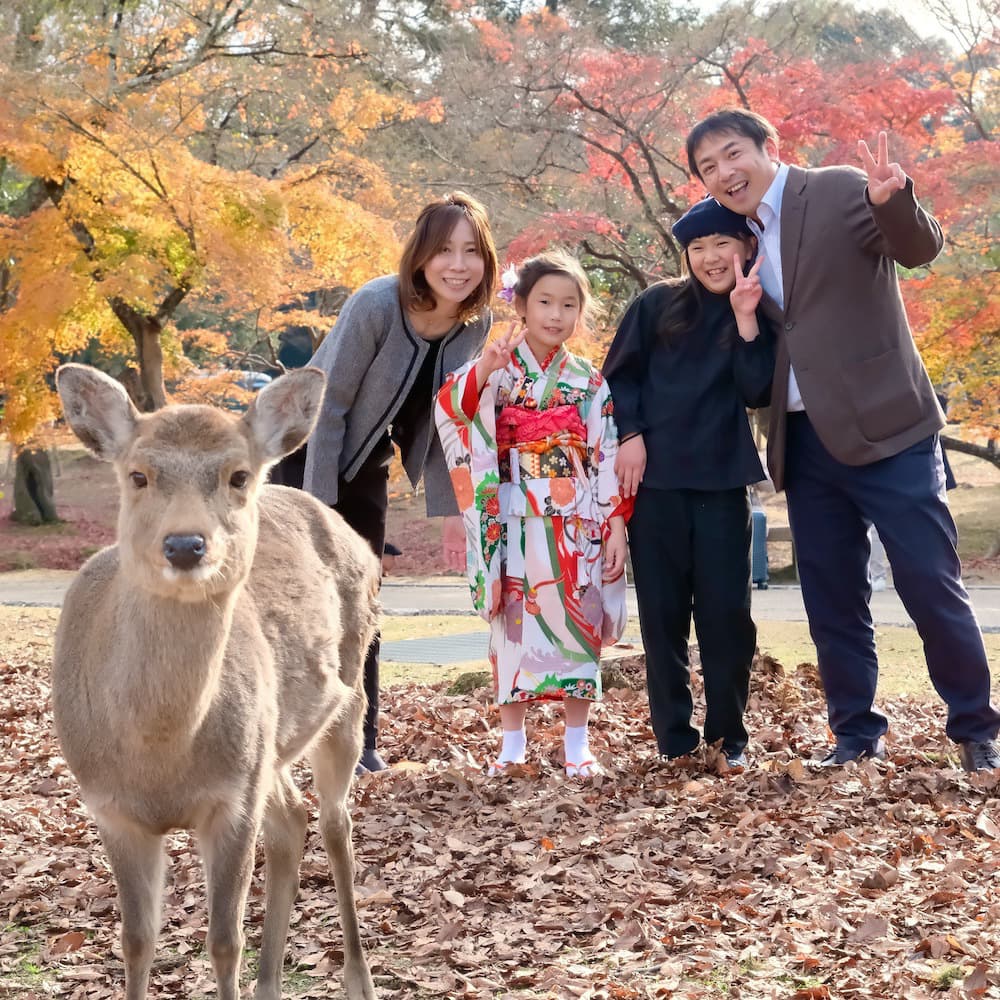 奈良の鹿と一緒に撮影している七五三を祝う家族