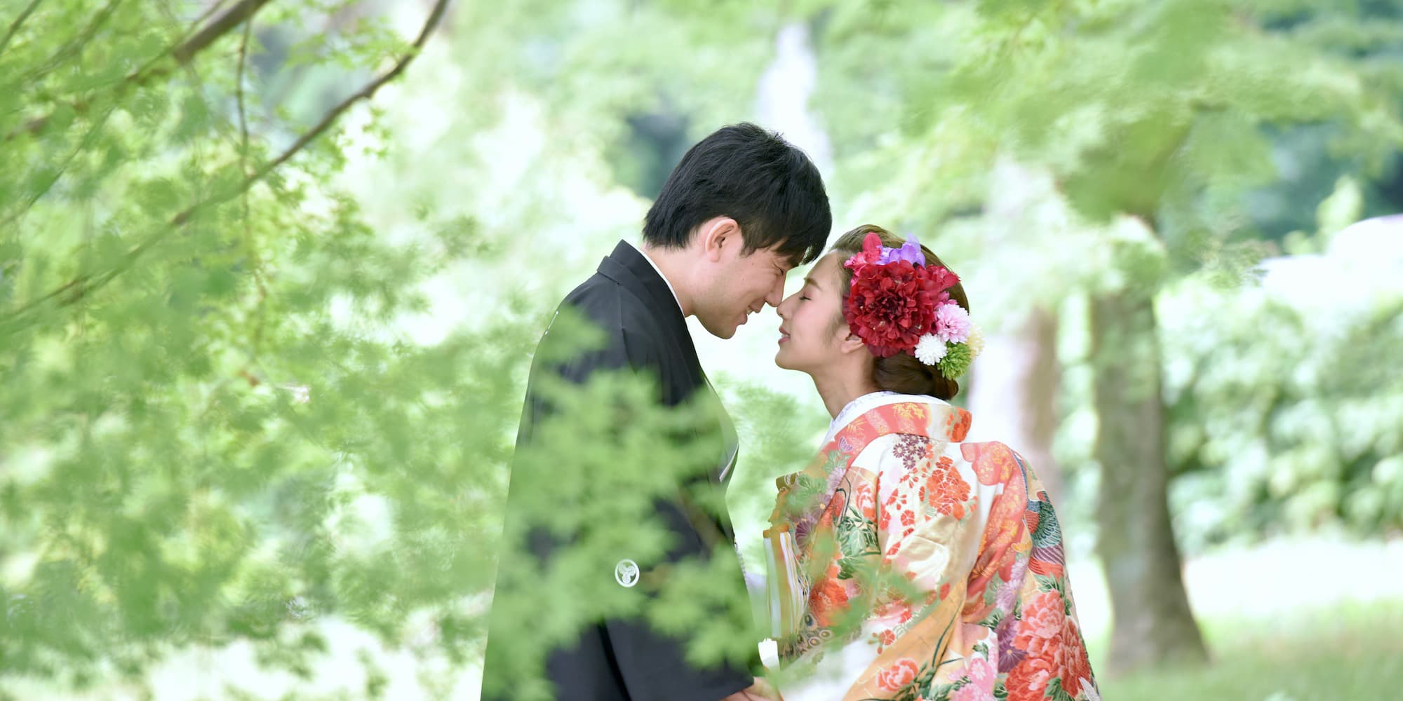 色打掛を着た花嫁様と紋付羽織袴を着た新郎様が顔をくっつけている