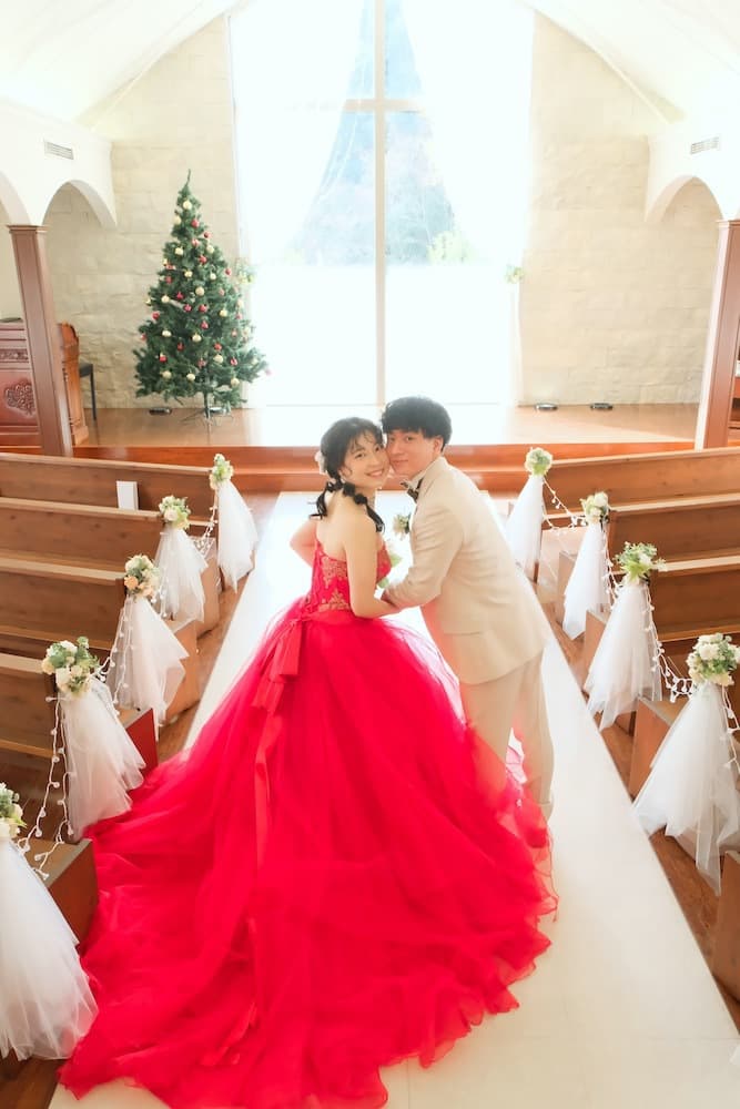 クリスマスツリーが飾られたチャペルで手をつないでいる新郎新婦