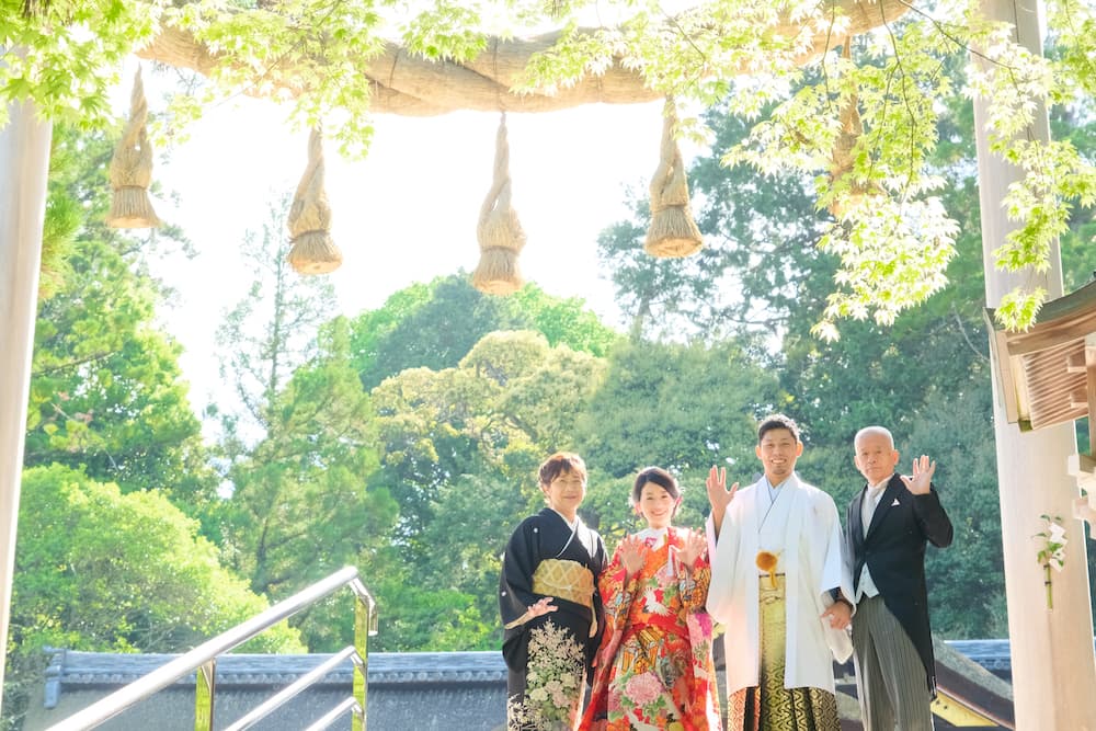 色打掛の花嫁様と紋付羽織袴の新郎様が家族や友人と写真を撮っている