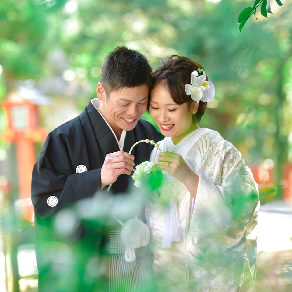白無垢を着た花嫁様と紋付羽織袴を着た新郎様が神社で結婚式を挙げている