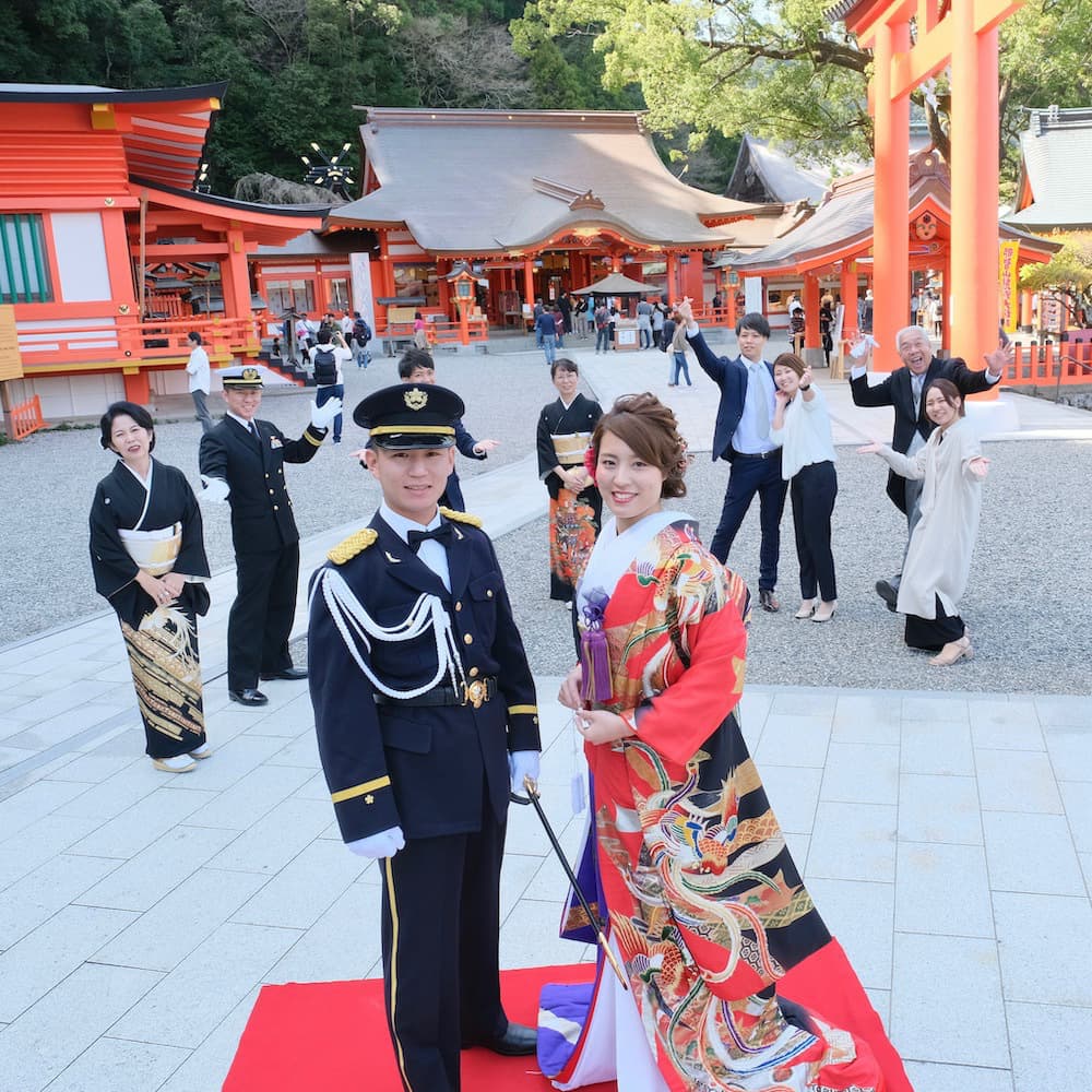 色打掛を着た花嫁様と紋付羽織袴を着た新郎様が神社で結婚式を挙げている
