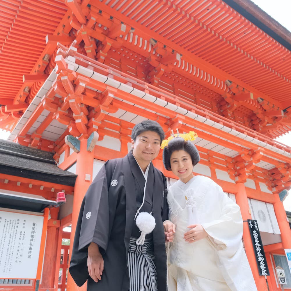 白無垢を着た花嫁様と紋付羽織袴を着た新郎様が神社で結婚式を挙げている