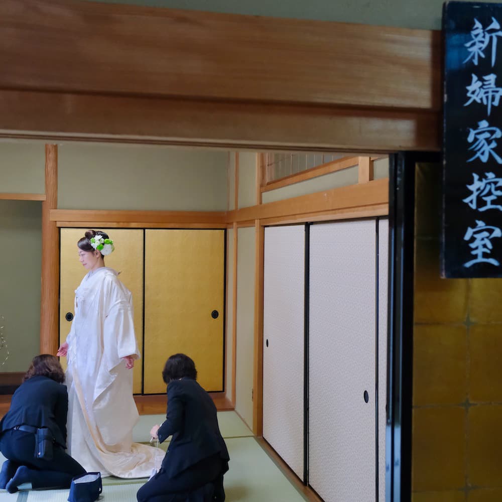 白無垢を着た花嫁様と紋付羽織袴を着た新郎様が神社で結婚式を挙げている