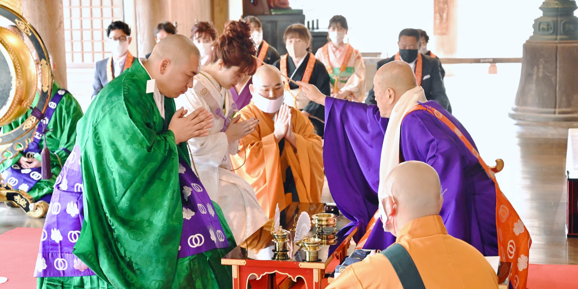 白無垢を着た花嫁様と紋付羽織袴を着た新郎様が寺院で結婚式を挙げている