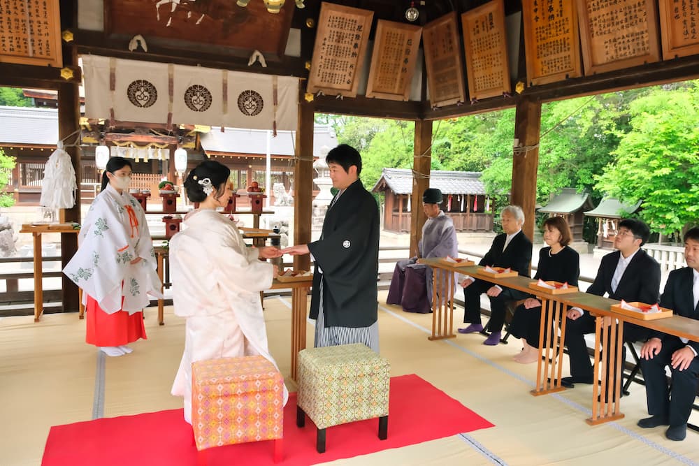 白無垢の花嫁様と紋付羽織袴の新郎様が結婚式を挙げている