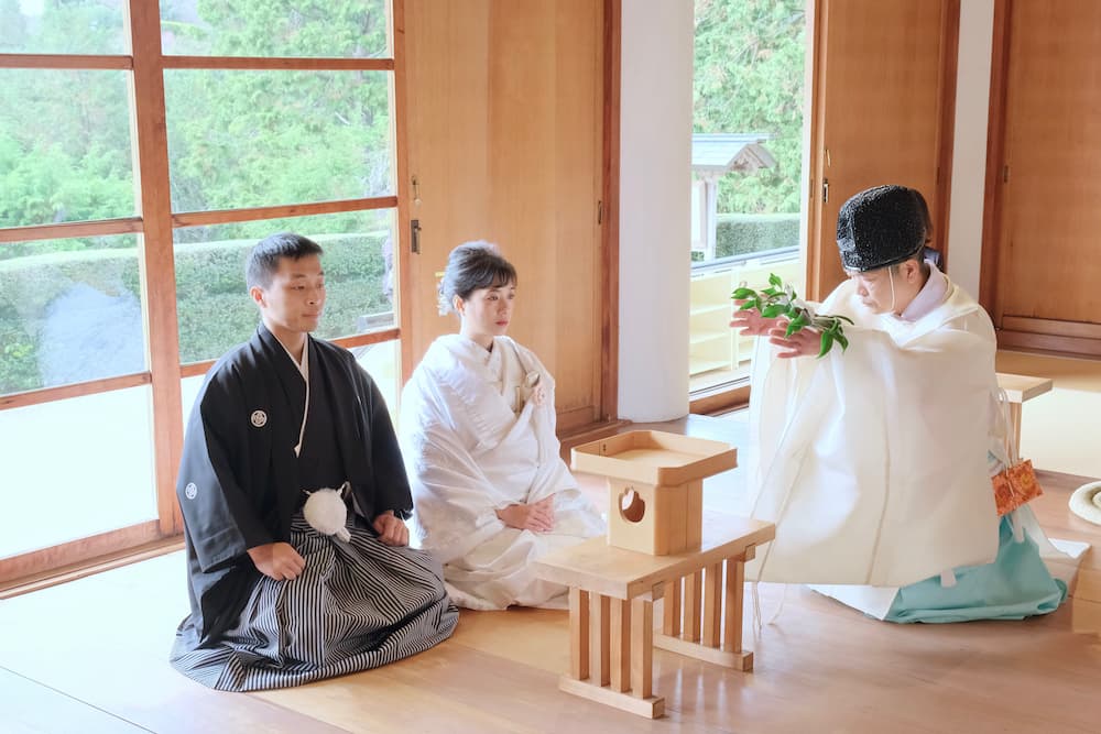 白無垢の花嫁様と紋付羽織袴の新郎様が結婚式を挙げている