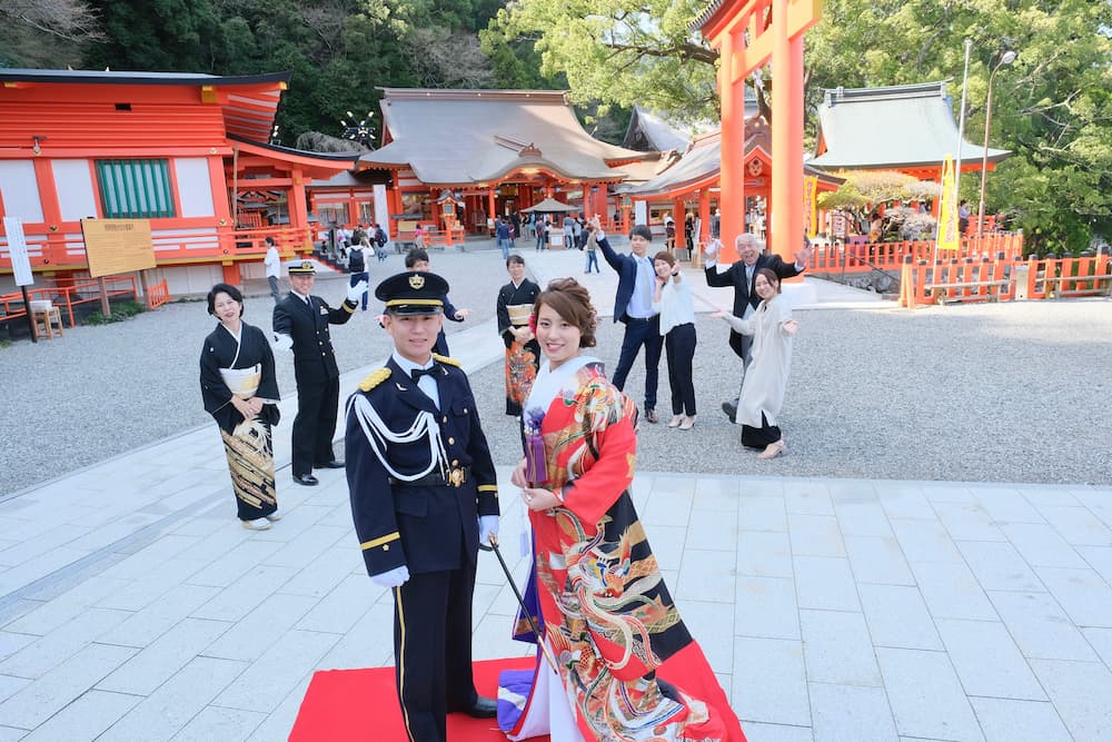 色打掛の花嫁様と紋付羽織袴の新郎様が家族や友人と写真を撮っている