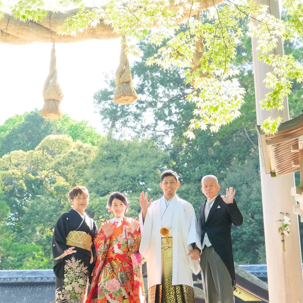 色打掛を着た花嫁様と紋付羽織袴を着た新郎様が神社で結婚式を挙げている