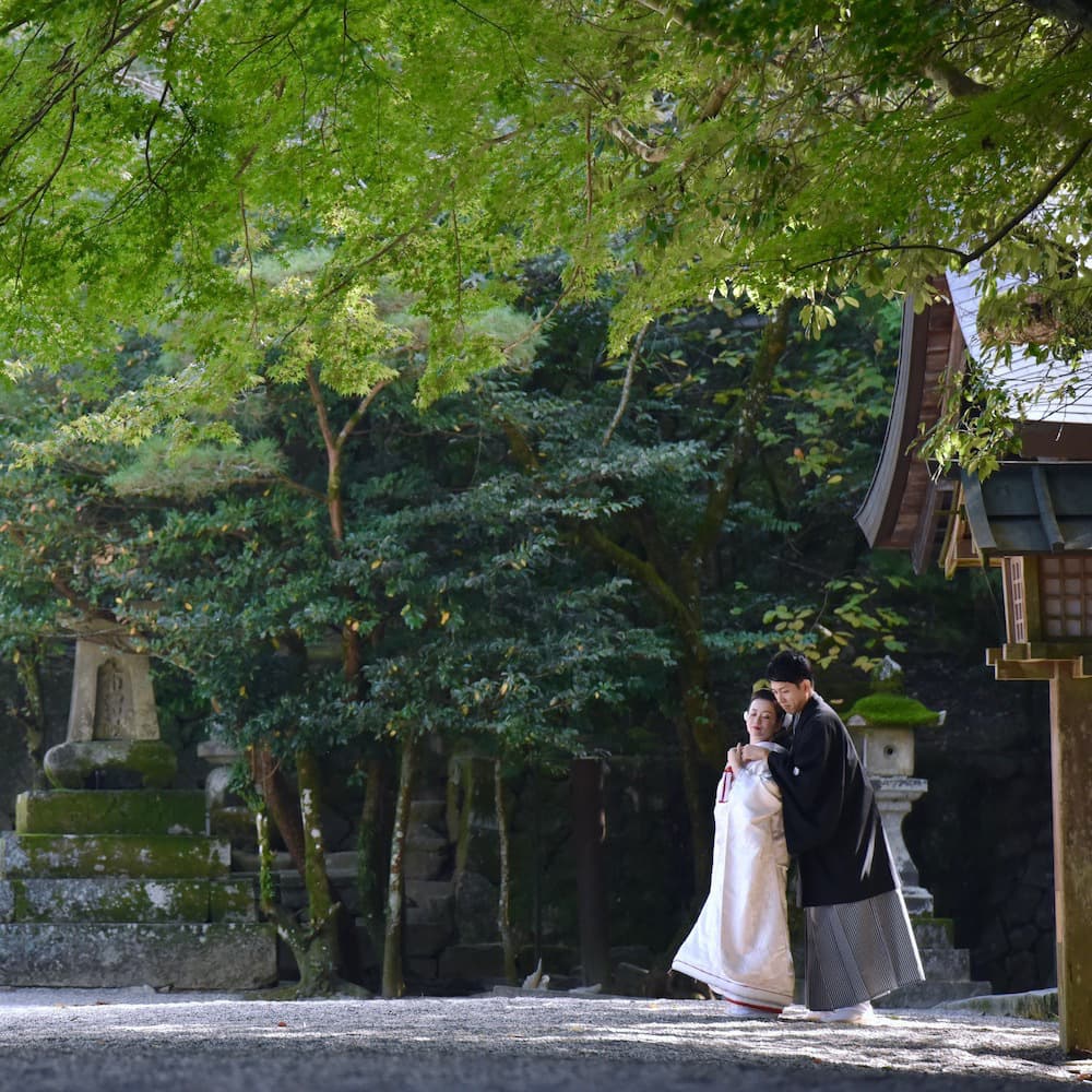 白無垢を着た花嫁様と紋付羽織袴を着た新郎様が神社で結婚式を挙げている