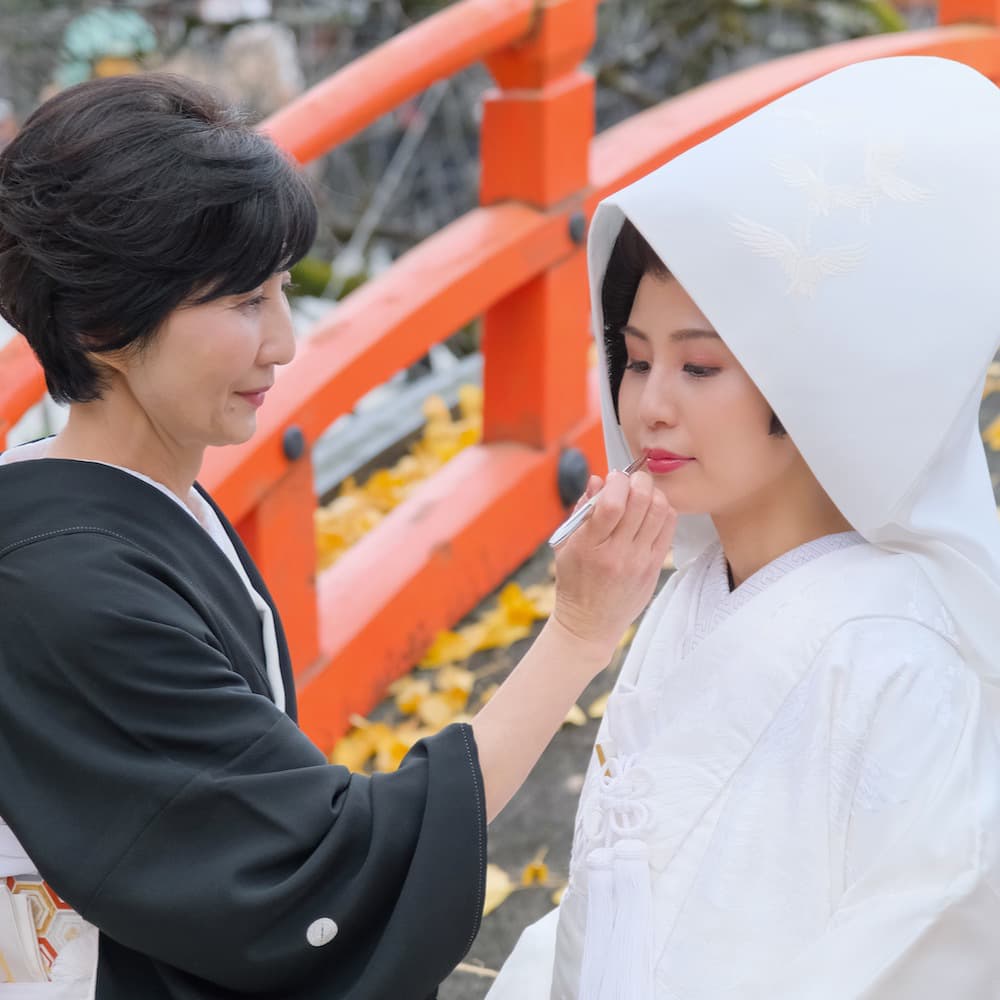 白無垢を着た花嫁様にお母様が口紅を塗ってあげている