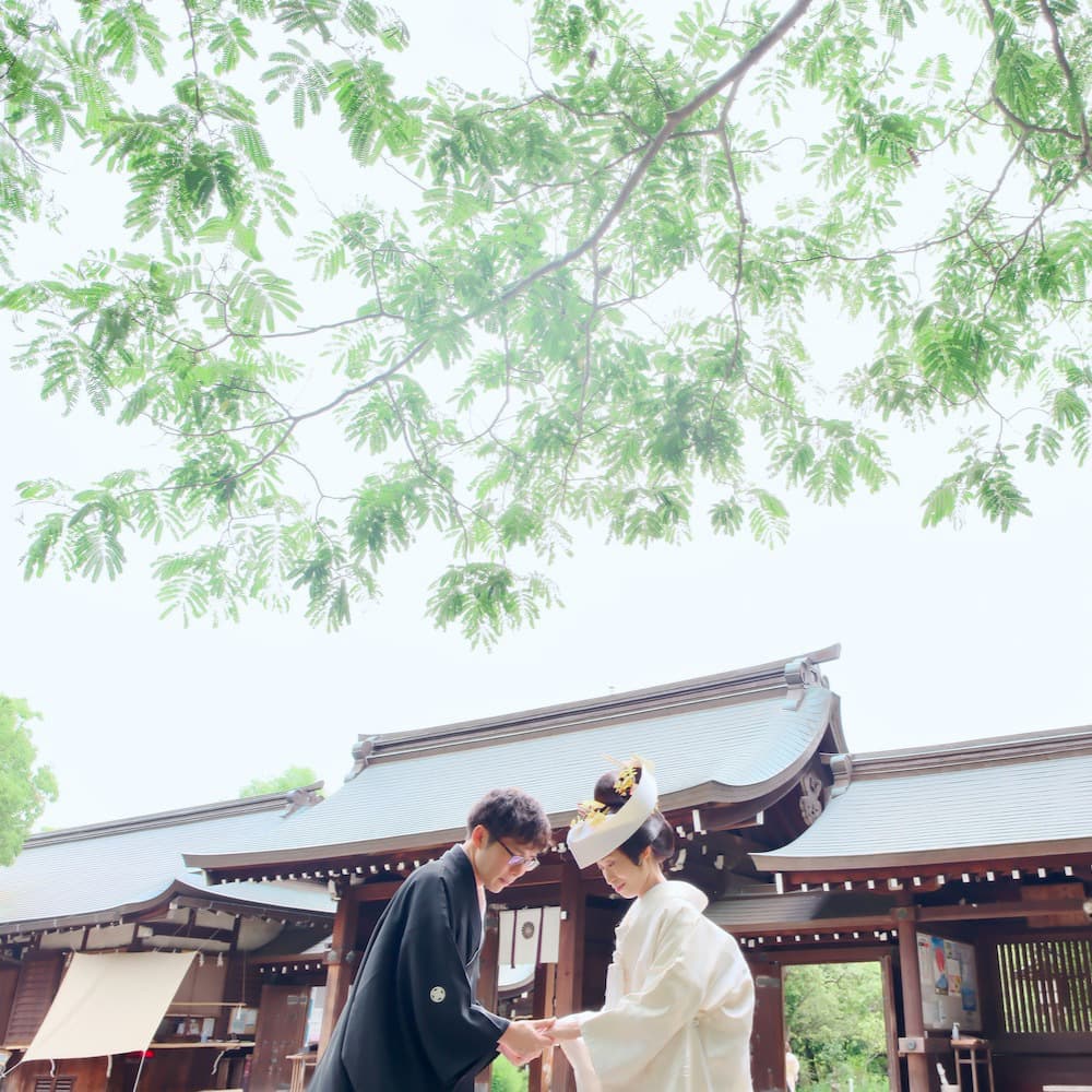 白無垢を着た花嫁様と紋付羽織袴を着た新郎様が神社で結婚式を挙げている