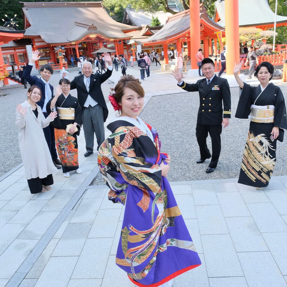 色打掛を着た花嫁様と紋付羽織袴を着た新郎様が神社で結婚式を挙げている