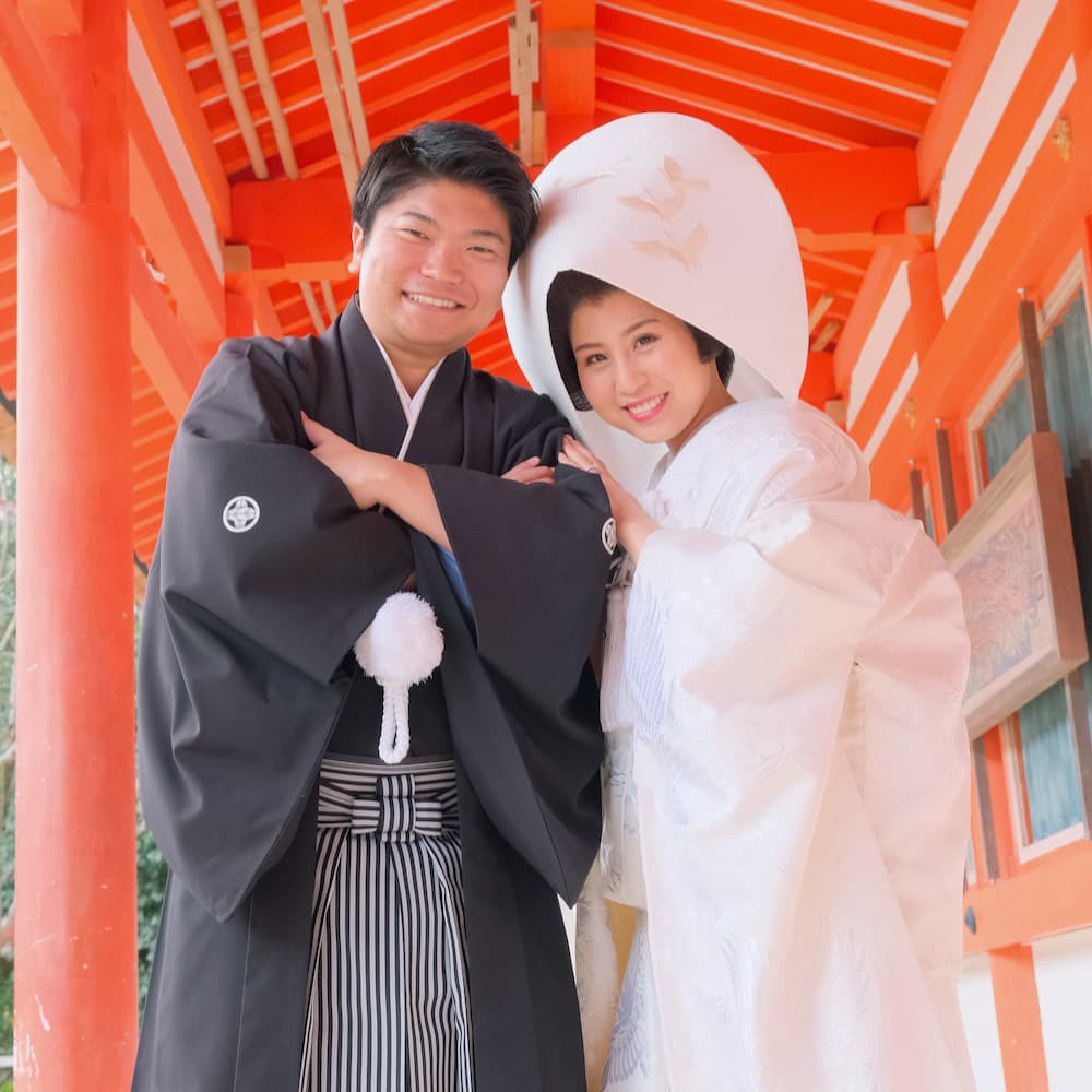 白無垢を着た花嫁様と紋付羽織袴を着た新郎様が神社で結婚式を挙げている