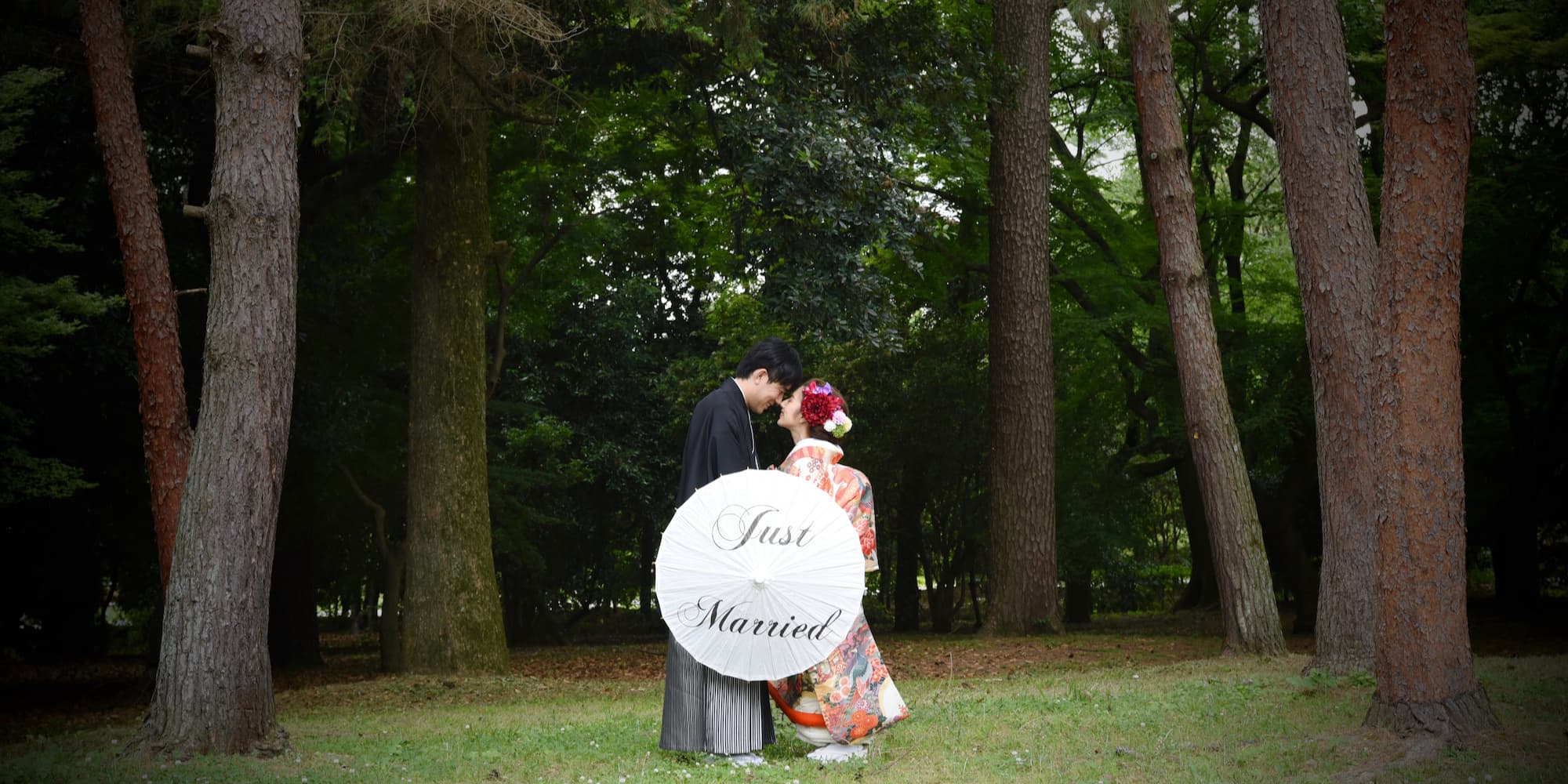 色打掛を着た花嫁様と紋付羽織袴を着た新郎様が和傘をさしている