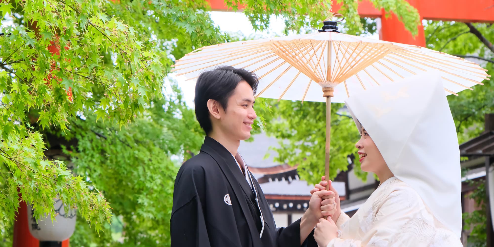 白無垢を着た花嫁様と紋付羽織袴を着た新郎様が神社で結婚式を挙げている