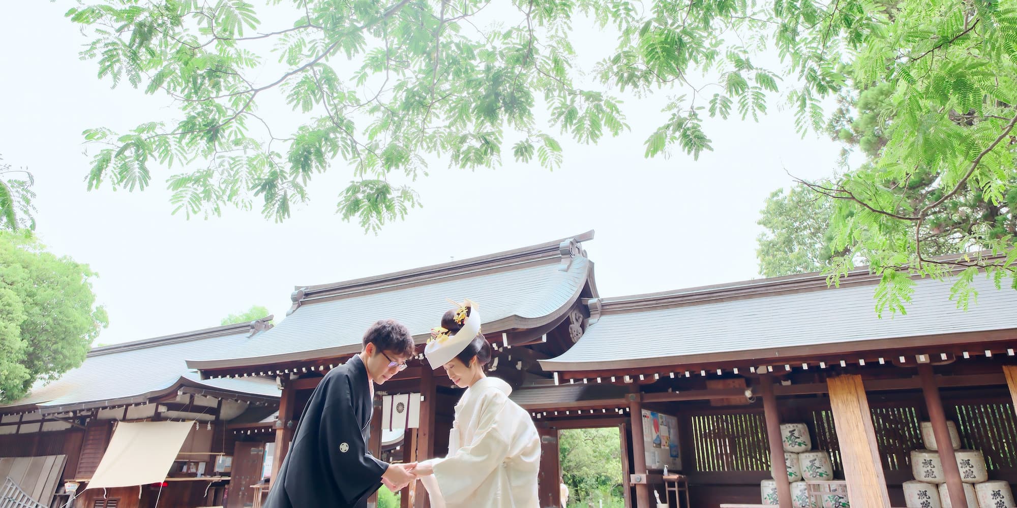 白無垢を着た花嫁様と紋付羽織袴を着た新郎様が神社で結婚式を挙げている