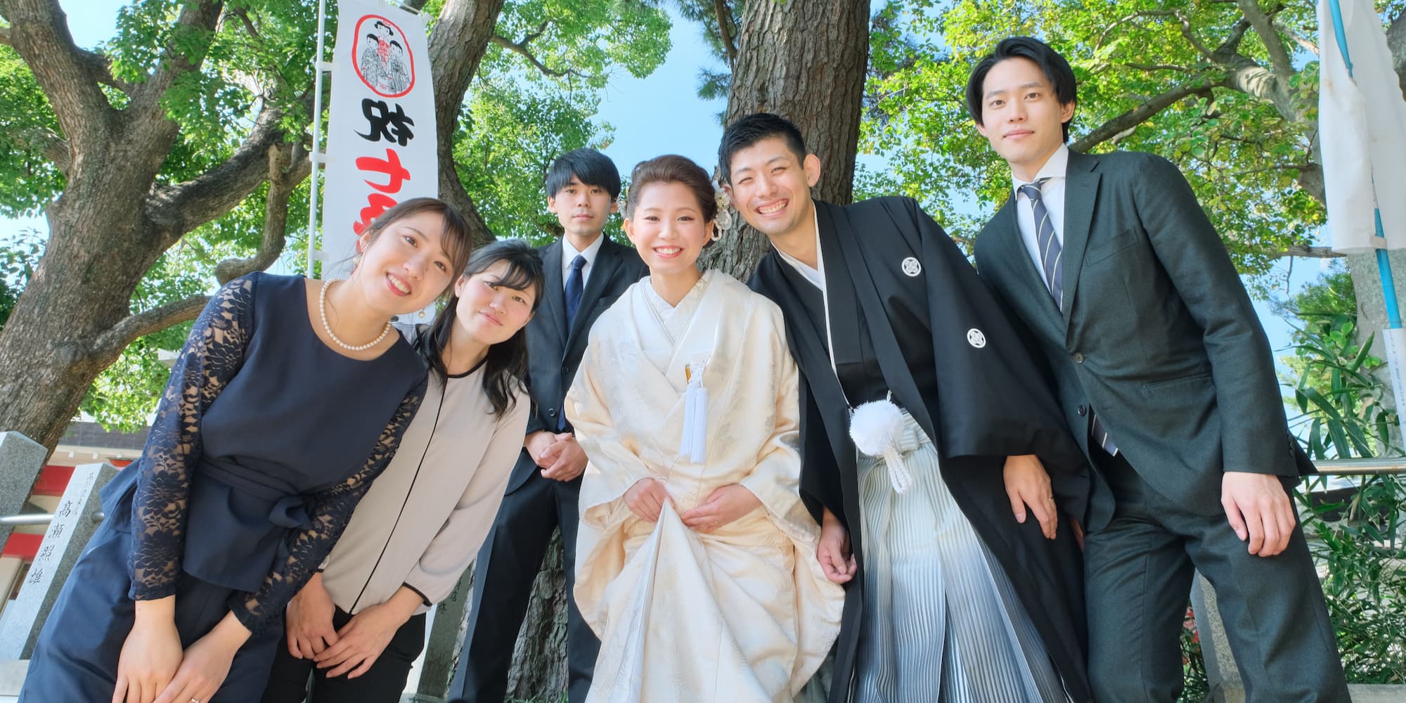 白無垢を着た花嫁様と紋付羽織袴を着た新郎様が友人たちと笑っている