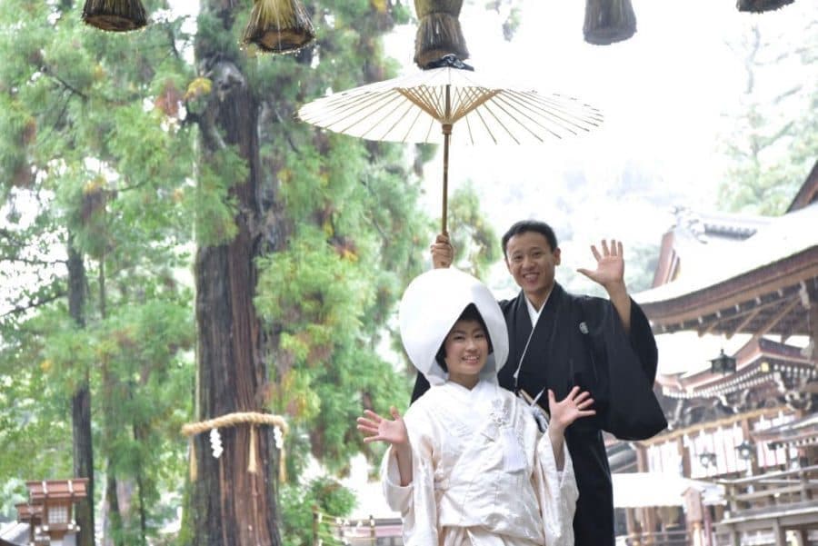 雨の日の大神神社で和傘をさす白無垢姿の新郎新婦