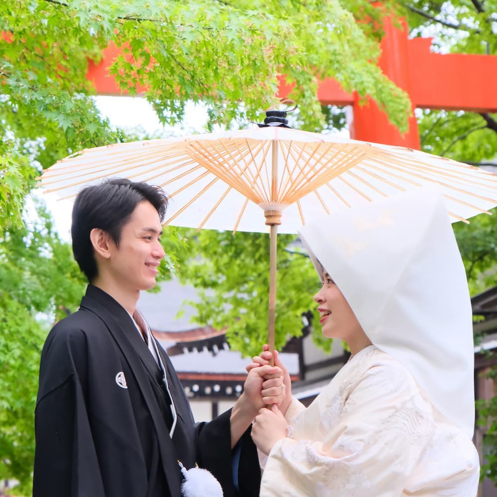 白無垢を着た花嫁様と紋付羽織袴を着た新郎様が神社で結婚式を挙げている