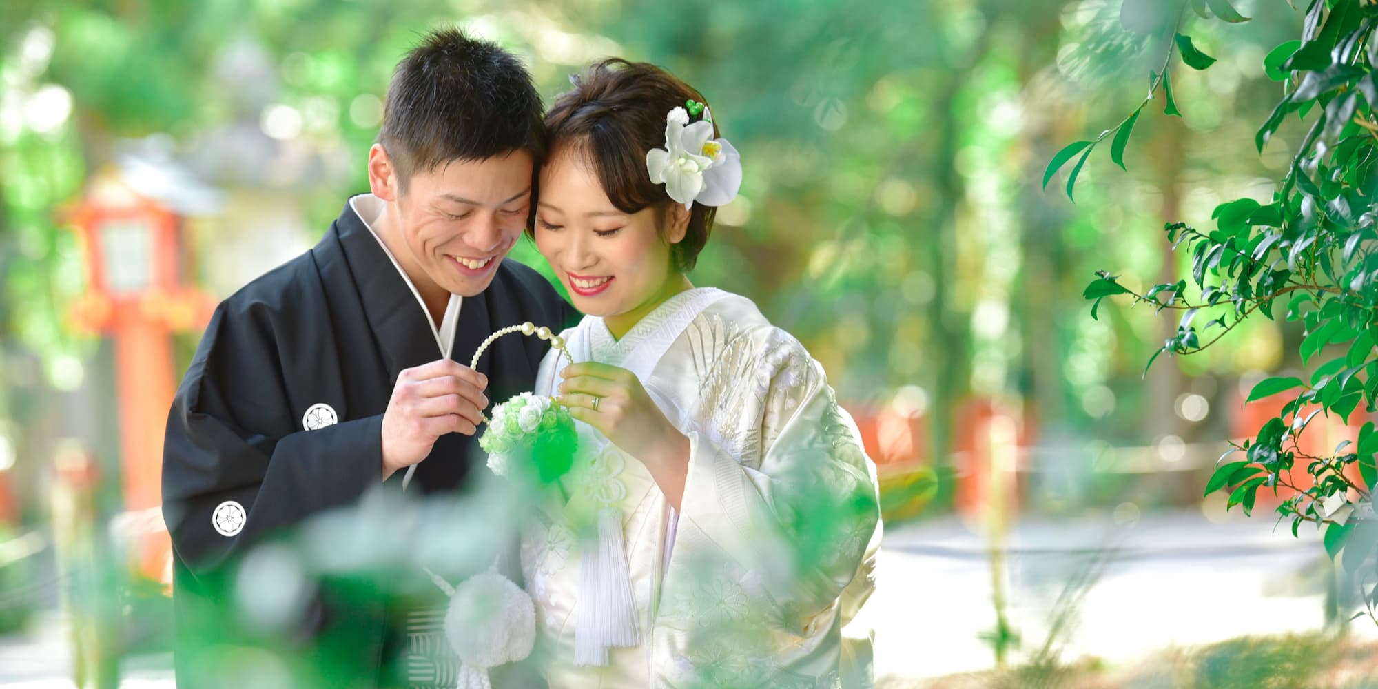 白無垢を着た花嫁様と紋付羽織袴を着た新郎様が神社で結婚式を挙げている