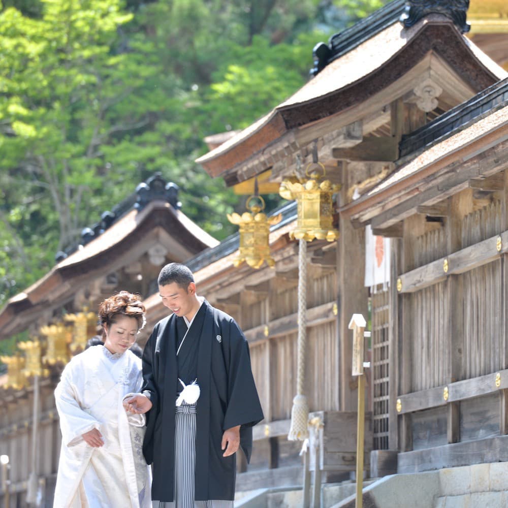 白無垢を着た花嫁様と紋付羽織袴を着た新郎様が神社で結婚式を挙げている