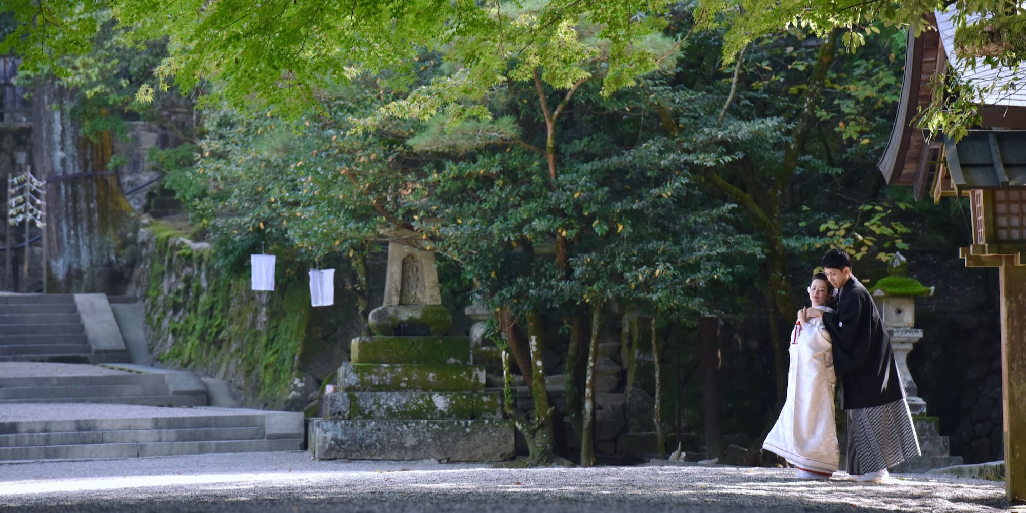 白無垢を着た花嫁様と紋付羽織袴を着た新郎様が神社で結婚式を挙げている