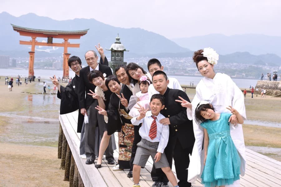 白無垢の花嫁様と紋付羽織袴の新郎様が家族や友人と写真を撮っている