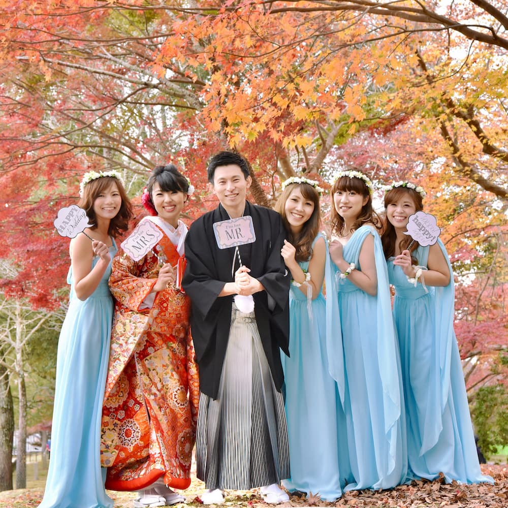 色打掛を着た花嫁様と紋付羽織袴を着た新郎様が神社で結婚式を挙げている