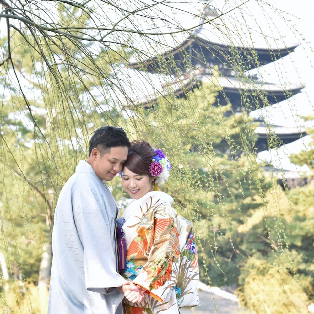 色打掛を着た花嫁様と紋付羽織袴を着た新郎様が神社で結婚式を挙げている