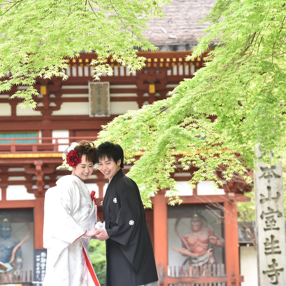 白無垢を着た花嫁様と紋付羽織袴を着た新郎様が神社で結婚式を挙げている