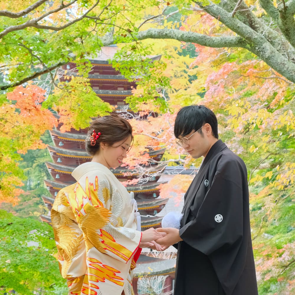 白無垢を着た花嫁様と紋付羽織袴を着た新郎様が神社で結婚式を挙げている