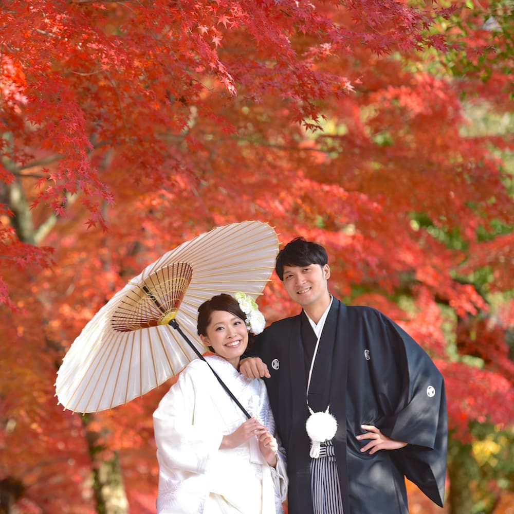 白無垢を着た花嫁様と紋付羽織袴を着た新郎様が神社で結婚式を挙げている