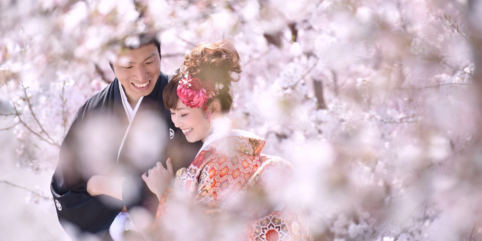 白無垢を着た花嫁様と紋付羽織袴を着た新郎様が友人たちと笑っている