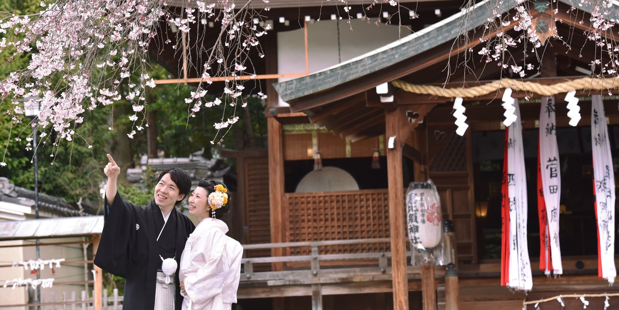 紅葉が美しい橋の上で色打掛を着た花嫁と紋付羽織袴の新郎