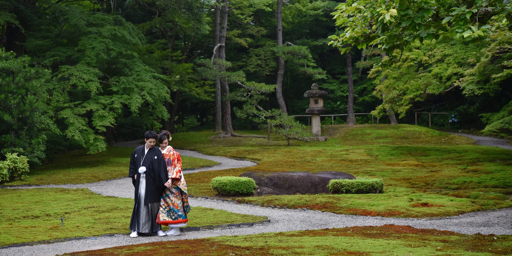 色打掛を着た花嫁様と紋付羽織袴を着た新郎様が和傘をさしている