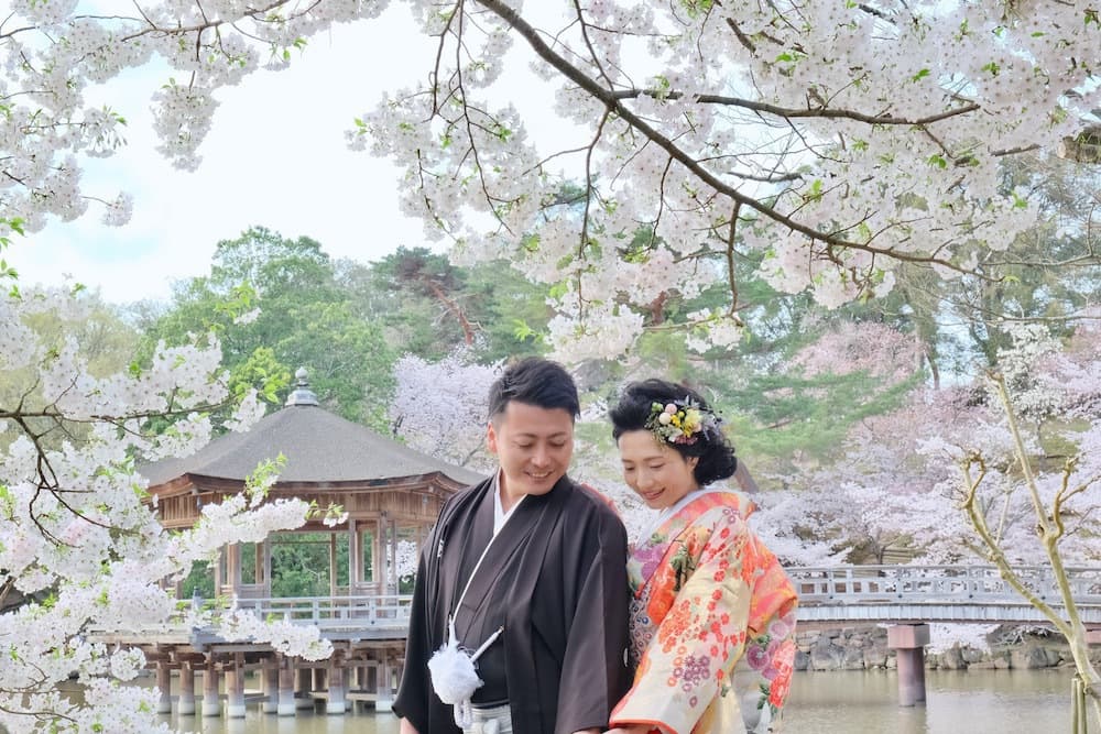 奈良の桜の前でフォトウェディングをしている新郎新婦