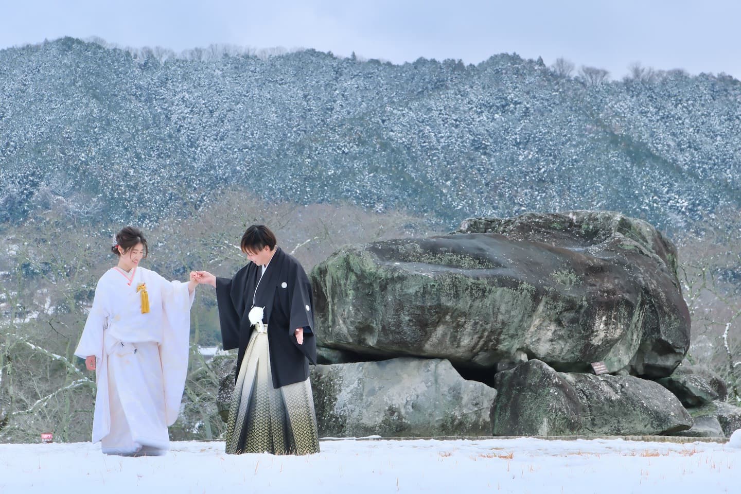 石舞台古墳の雪景色で撮影する白無垢と紋付袴の新郎新婦