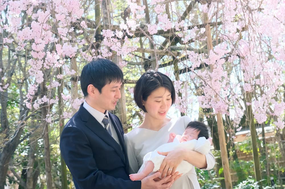 桜の下で撮った神社でのお宮参りの写真