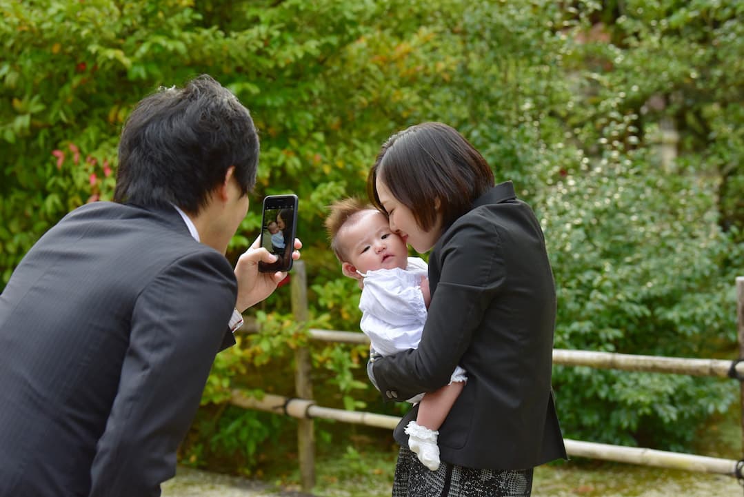 お宮参りの写真を撮影するパパの写真