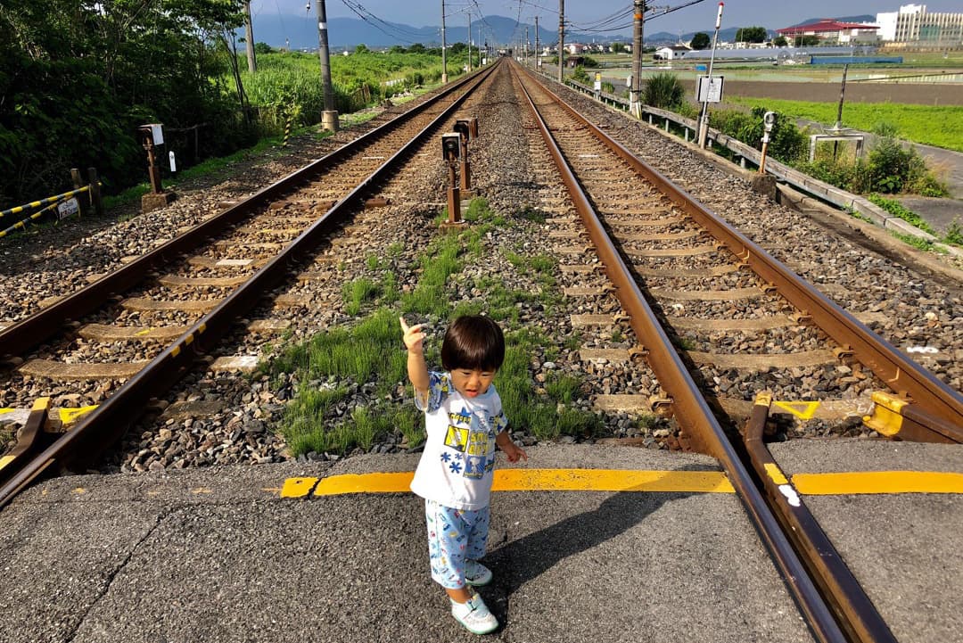 線路で手を上げて渡る男の子の写真