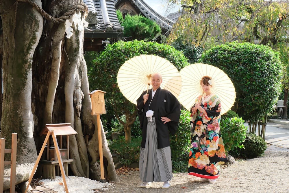 神社で和傘をさして記念写真を撮影している夫婦