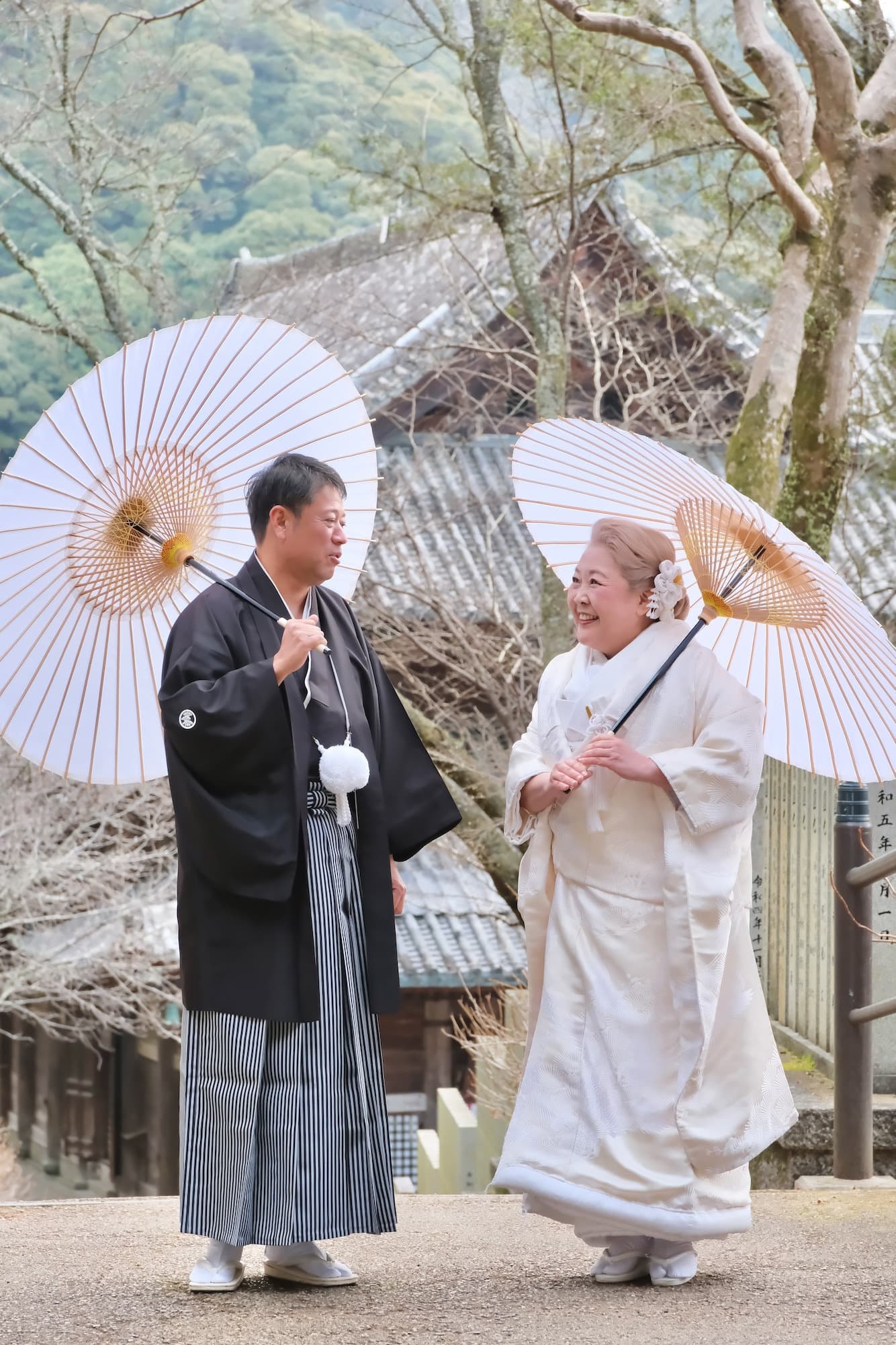 神社で白い和傘をさしている新郎新婦
