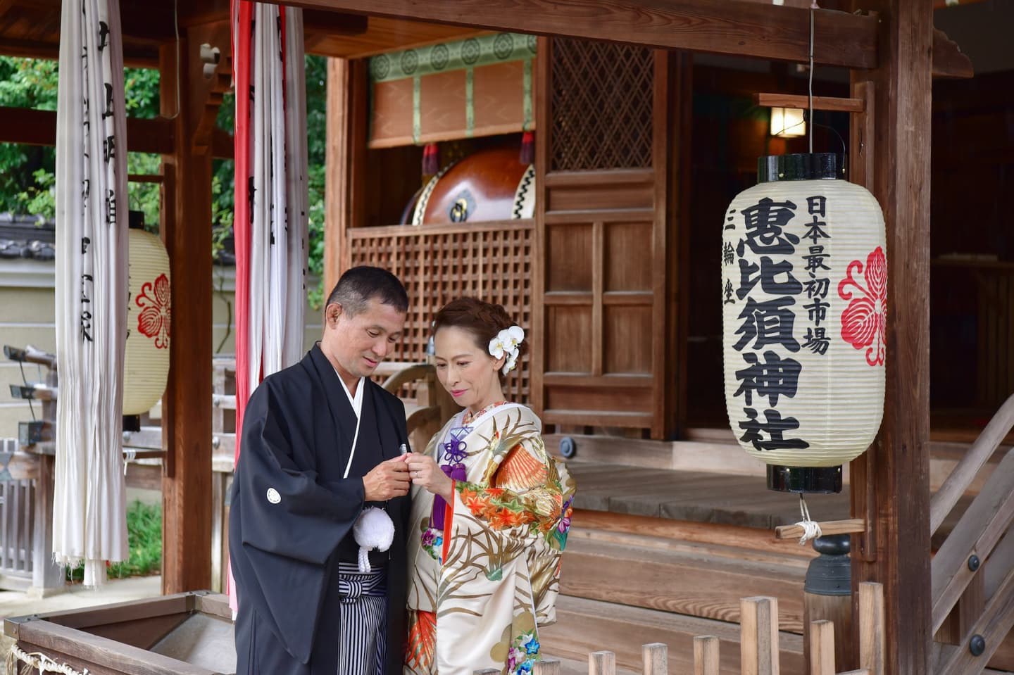 神社で白い和傘をさしている夫婦